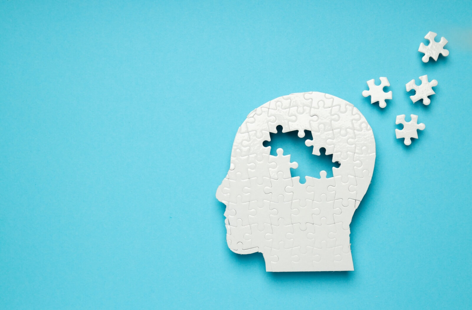 A head-shaped puzzle with 4 missing pieces lying nearby on a blue background.