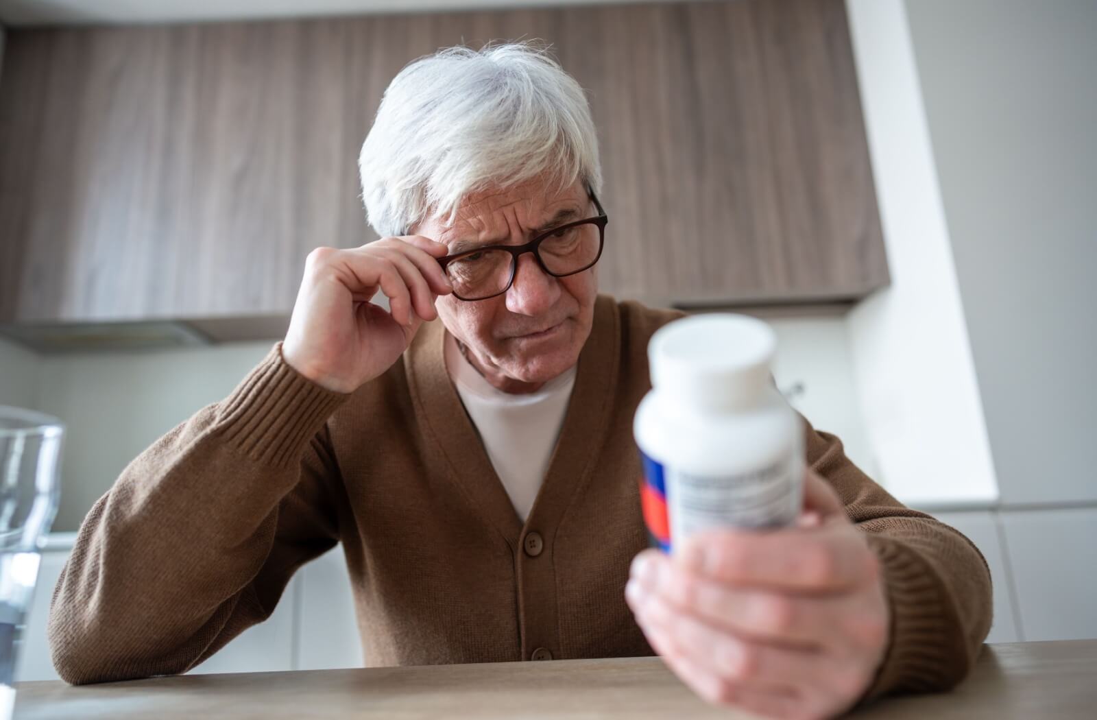 A senior examines a pill bottle, trying to remember whether they’ve taken their dose; a sign that memory care may be helpful