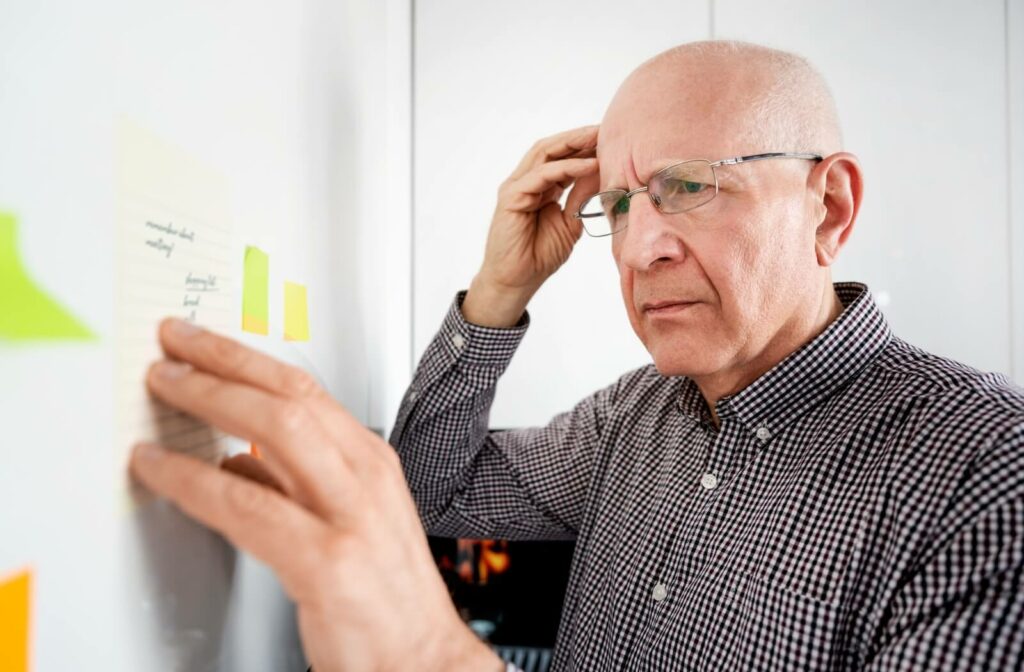 An older adult with dementia reads a sticky note to remember their daily tasks.