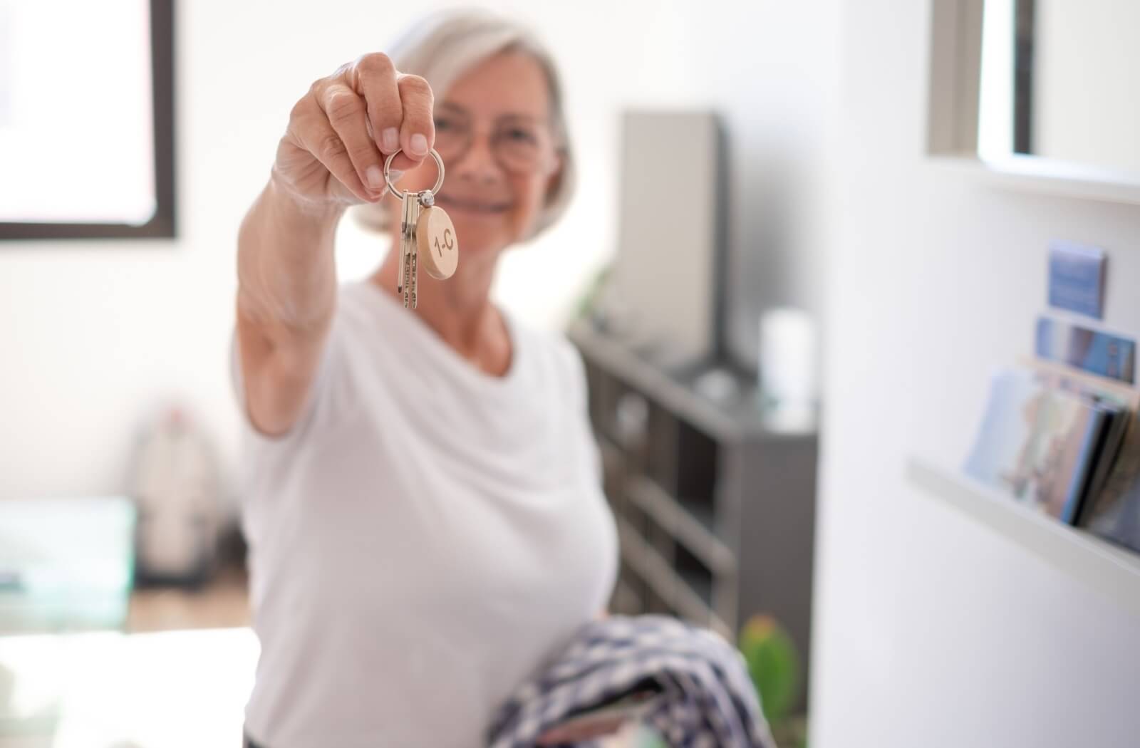 Senior women holding keys of her senior living suite after downsizing