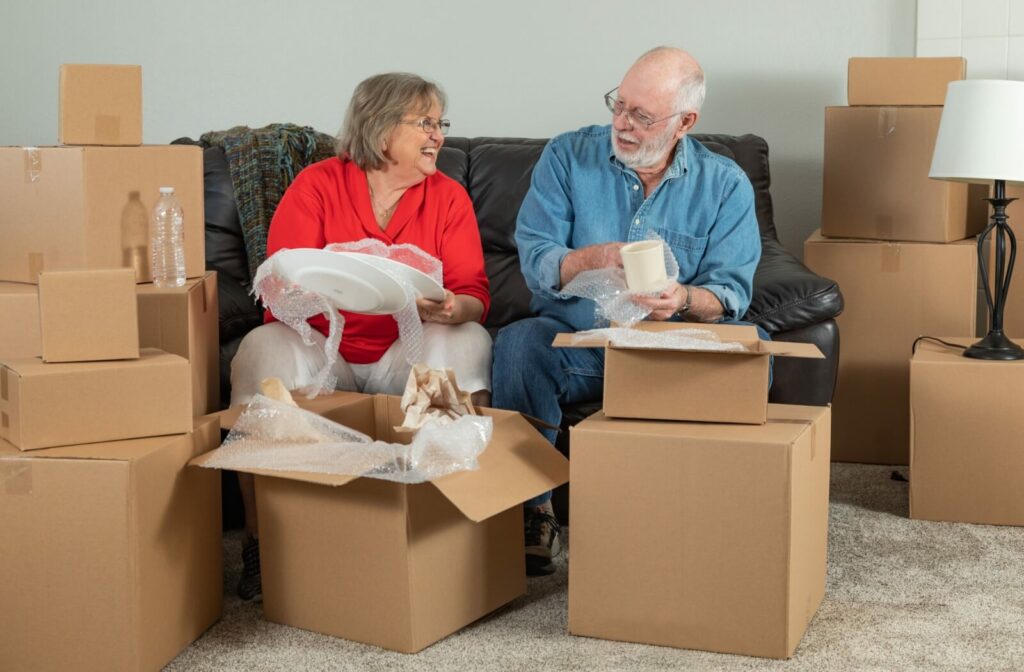 A married older couple unpacking their belongings from moving boxes in their new home in assisted living.